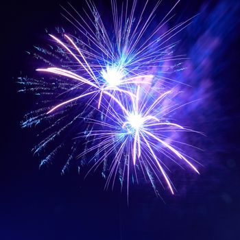 Blue colorful fireworks on the night black sky background. Holiday celebration.