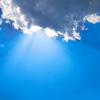 Beautiful blue sky with sunbeams and clouds. Sun rays.