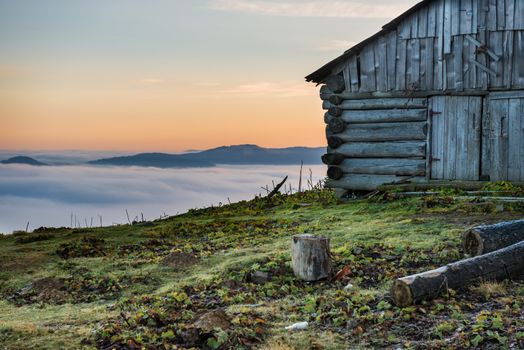 Old house in front of beautiful nature with clouds ocean, field of grass and mountains