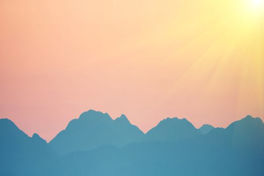 Beautiful orange sunset over mountains. Bright sun with sunrays. Cagliari, Sardinia, Italy.