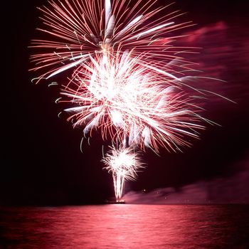 Red colorful holiday fireworks on the black sky background.