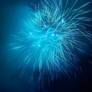 Blue colorful fireworks on the black sky background. Holiday celebration.