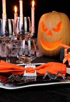 Napkin clamped in his teeth on a plate with spiders Halloween table