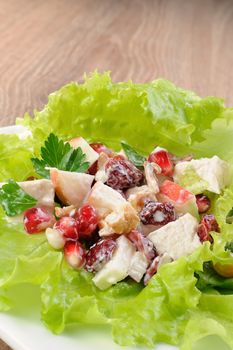 Salad with chicken, pomegranate, cranberries, walnuts seasoned in milk sauce lettuce leaves