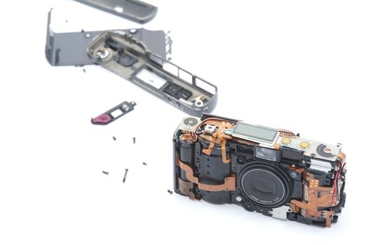 Exploded or dismantled camera laying on white background with various pieces trailed behind it