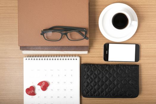 office desk : coffee with phone,stack of book,eyeglasses,wallet,calendar,heart on wood background