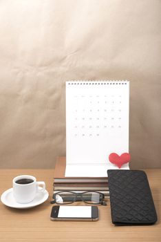 office desk : coffee with phone,stack of book,eyeglasses,wallet,calendar,heart on wood background