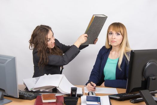 Two young beautiful girls colleagues sitting at the same desk in the office