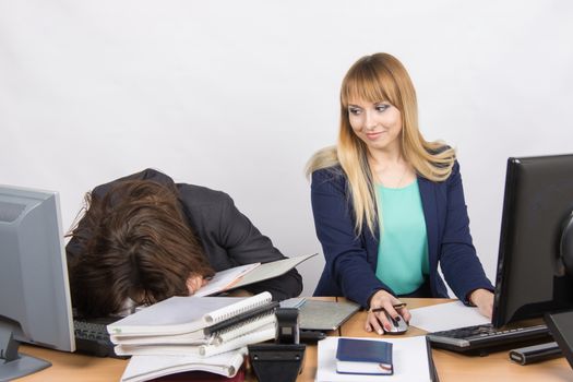 Two young beautiful girls colleagues sitting at the same desk in the office