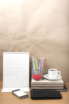 office desk : coffee with phone,wallet,calendar,heart,color pencil box,stack of book,heart on wood background