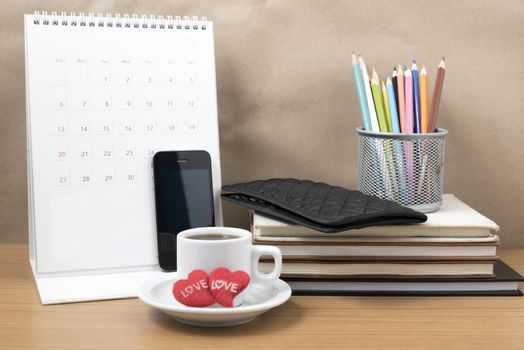office desk : coffee with phone,wallet,calendar,heart,color pencil box,stack of book,heart on wood background
