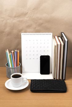 office desk : coffee with phone,wallet,calendar,color pencil box,stack of book on wood background