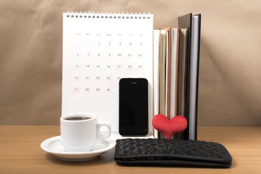 office desk : coffee with phone,wallet,calendar,heart,stack of book on wood background