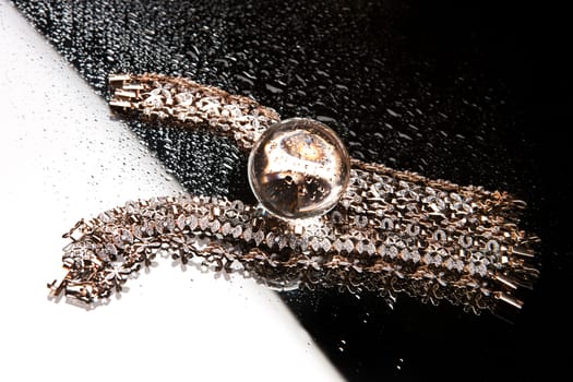 Golden bracelets on a black glass background with white highlight