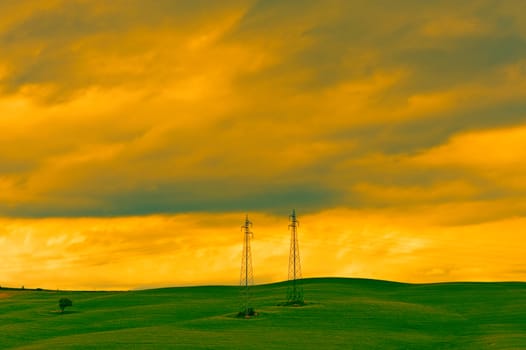 High-voltage Power Line Passes through the Green Sloping Meadows of Tuscany, Vintage Style Toned Picture