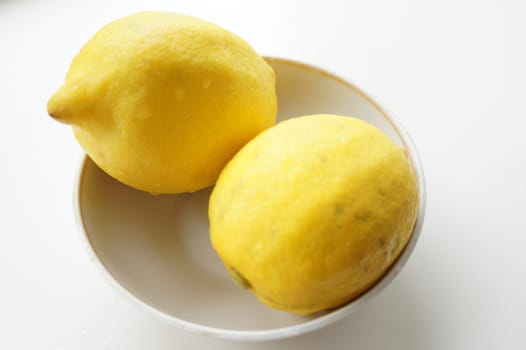 Yellow ripe lemons on a small white saucer