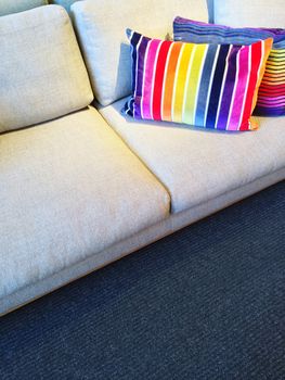 Comfortable sofa with bright rainbow color striped cushions.