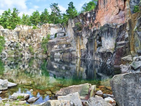 Picturesque lake in Sweden, surrounded by rocks and trees. Ancient stone quarry, abandoned many years ago.