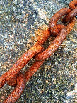 Old rusty iron chain on mossy stone background.