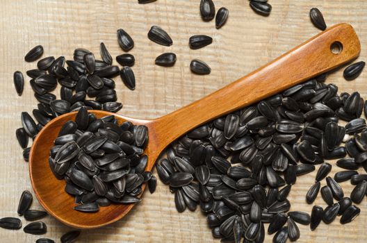 Selected sunflower seeds in a wooden spoon and scattered on the old wooden Board