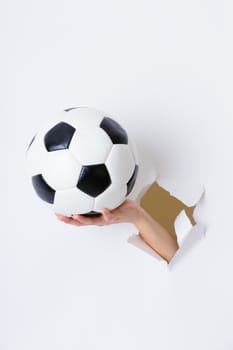 Hand through the hole in paper with soccer ball