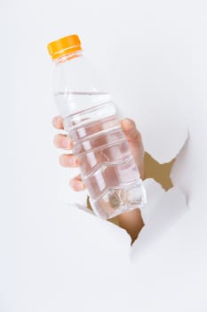 Hand through the hole in paper with plastic bottle