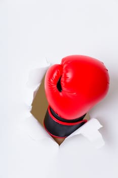 Hand in boxing glove through paper hole