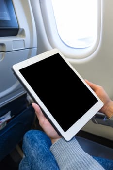 Woman using digital tablet on in plane