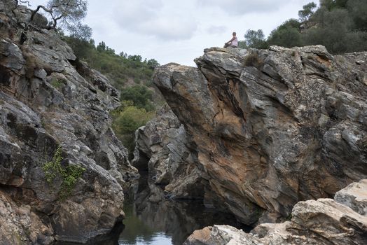 woman sitting on the high rocks of pego des pias in portugal alentejo area