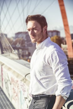 Handsome young man outside wearing white shirt, looking at camera, day shot.