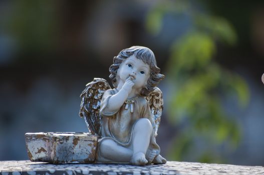 Angel watching over a tombstone. Cemetery figurine. Aged marble