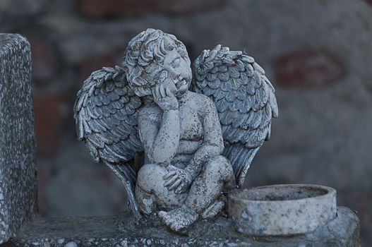 Angel watching over a tombstone. Cemetery figurine. Aged marble