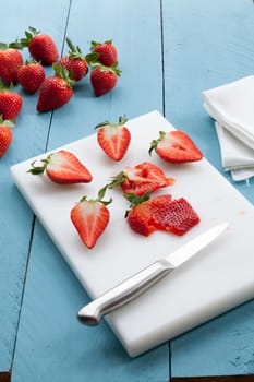 Wild strawberries placed on blue wooden background and illuminated with natural light