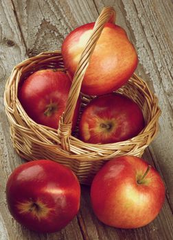 Arrangement of Apples Red Delicious in Wicker Basket closeup on Rustic Wooden background