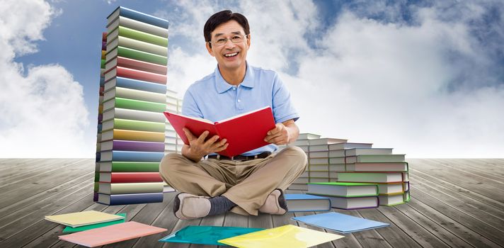 Smiling man reading books against steps made of books against sky