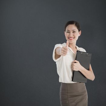 Woman gesturing thumbs up with people waiting for interview against grey background