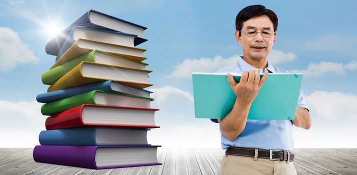 Elderly man holding a green folder against stack of books against sky