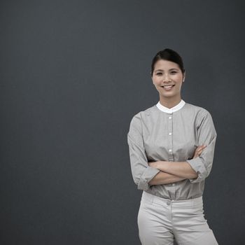 Selfassured businesswoman with folded arms  against grey background