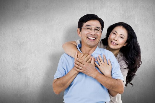 Smiling couple holding each other against white and grey background