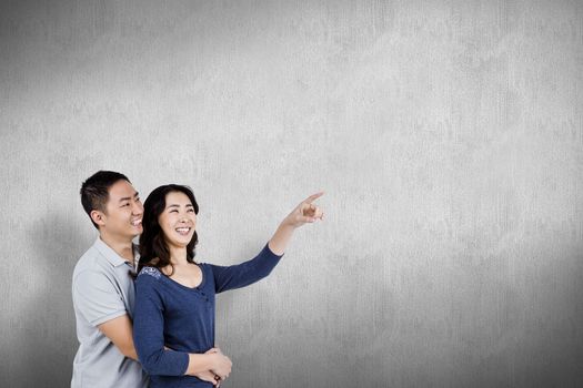 Happy couple with woman pointing up against white and grey background