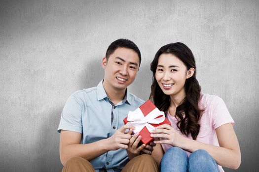 Happy couple holding gift box against white and grey background