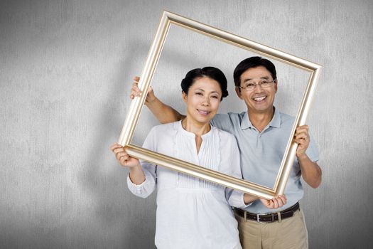 Older asian couple with frame against white and grey background