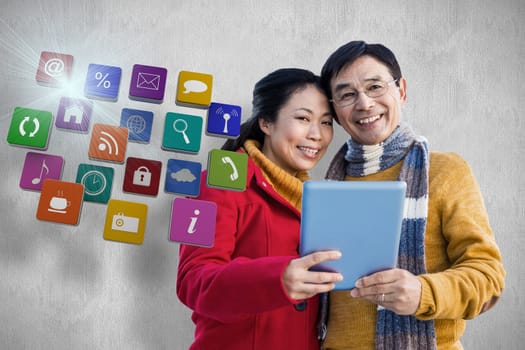 Asian couple on balcony using tablet against white and grey background
