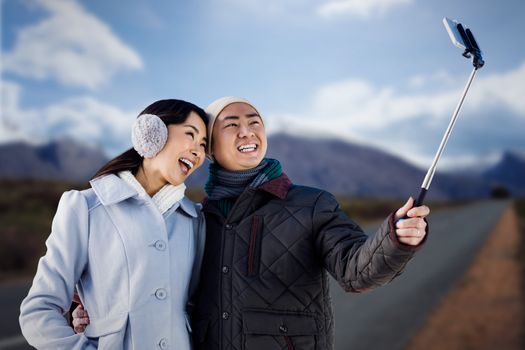 Couples taking funny pictures using smartphone against high angle view of road by mountains 