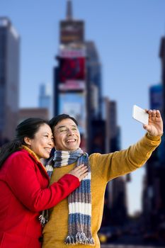 Older asian couple on balcony taking selfie against view of building
