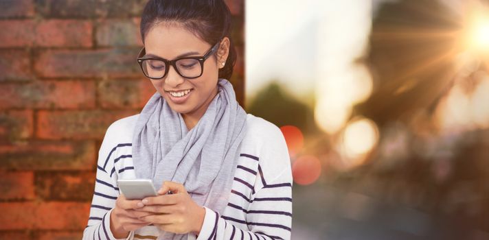 Smiling Asian woman using smartphone against wall of a house