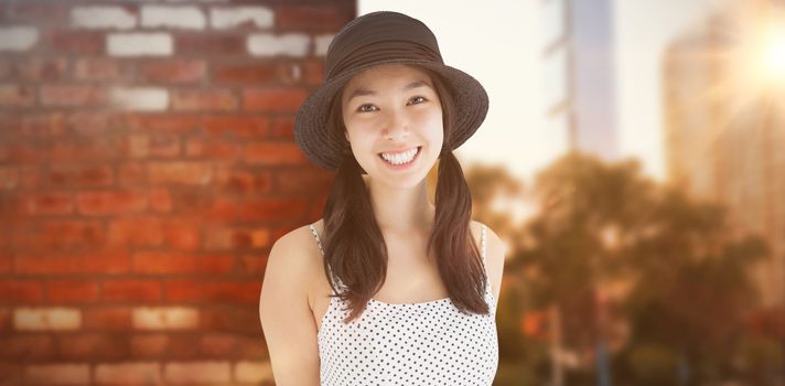 Cheerful woman with a polka dot dress and hat against wall of a house