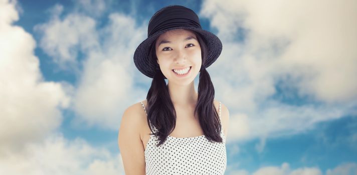 Cheerful woman with a polka dot dress and hat against road leading out to the horizon