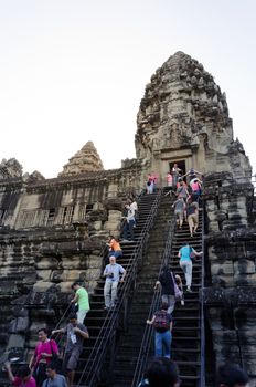 Siem Reap, Cambodia - December 4, 2015: Tourists climb to a praying tower at Angkor Wat. The temple is at the top of the high classical style of Khmer architecture. It has become a symbol of Cambodia,