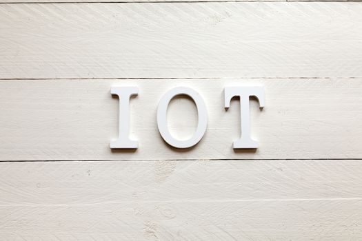 White letters representing the acronym of the Internet of things concept on wooden background